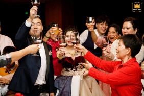 At a hotel in Shenzhen, China, the wedding couple cheers with family and friends, creating a lively and joyous atmosphere with glasses raised.